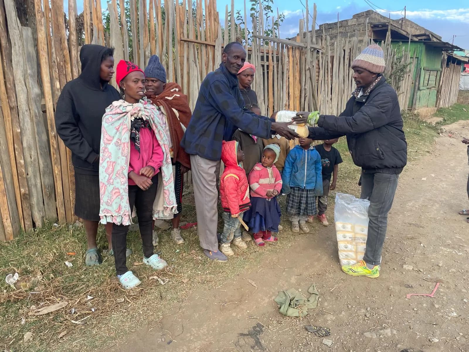 Mehl und Speiseöl werden in Kenia an Familien übergeben, Kinder stehen daneben